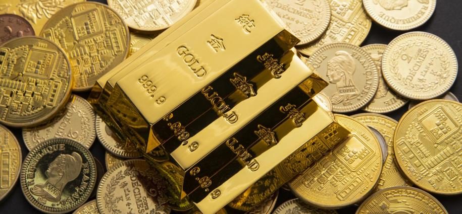 Gold bullion bars stacked on a pile of gold coins