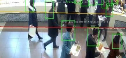 AI camera feed tracking people in a corridor with detection boxes and counting lines